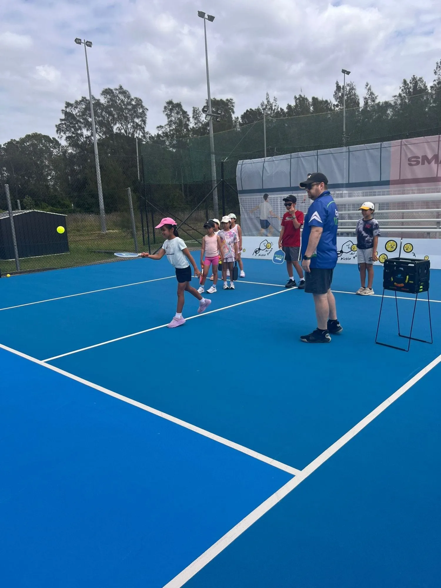A young player practising a forehand with a Play Pickle coach during a drill